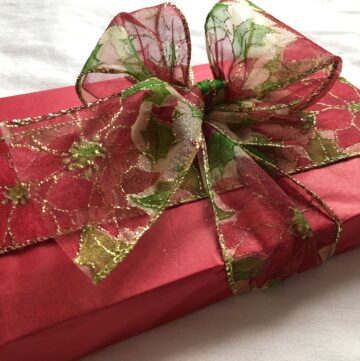 christmas-gift-wrapped-in-red-paper-decorated-with-a-ribbon-tied-in-a-bow