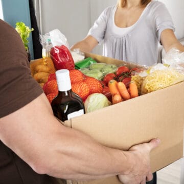 Close-up Of A Delivery Man Giving Grocery Cardboard Box To Woman