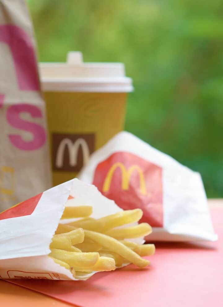 McDonald's take away paper bag and junk food on wooden table outdoors